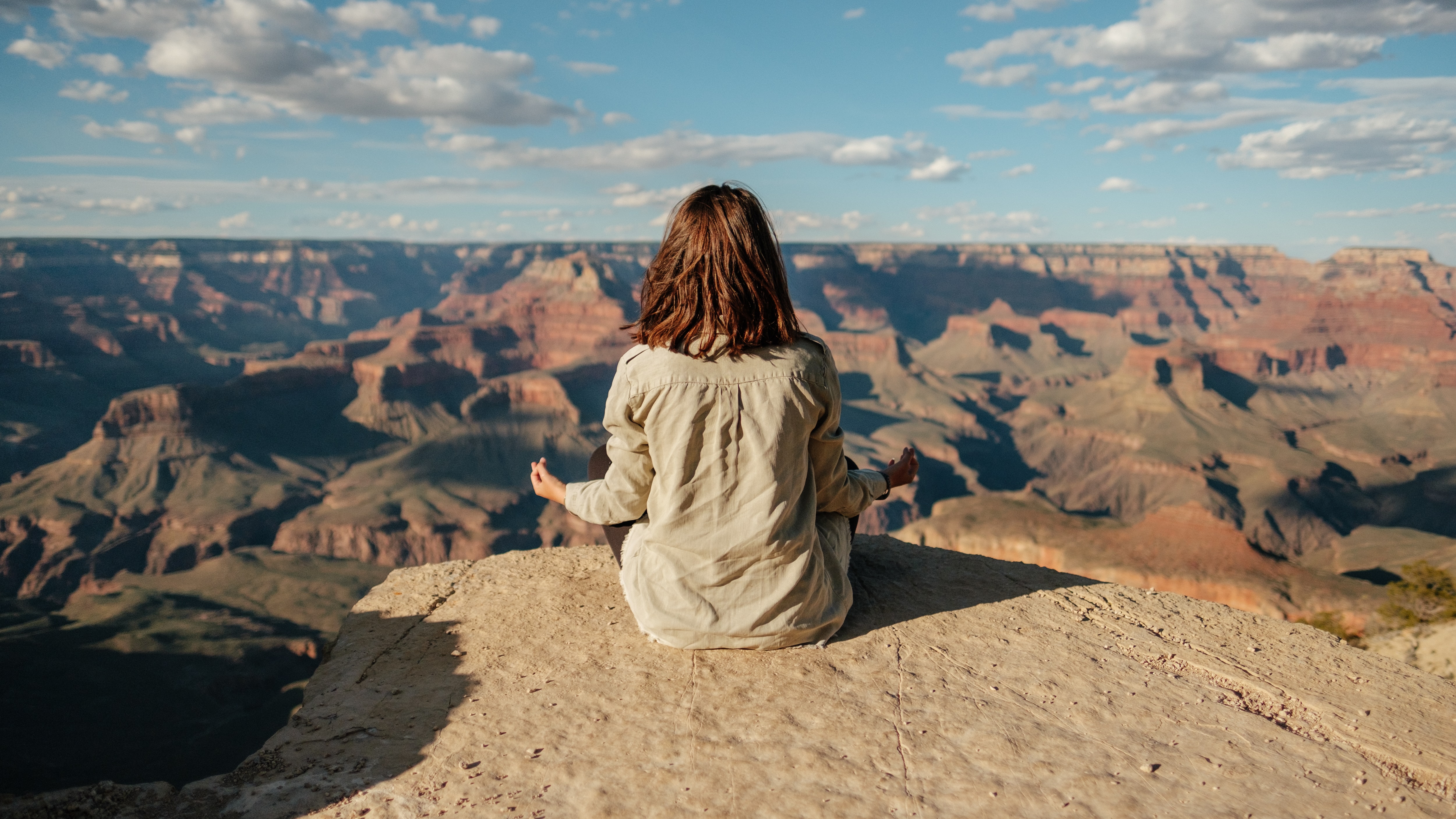 woman meditating on top of a canyon