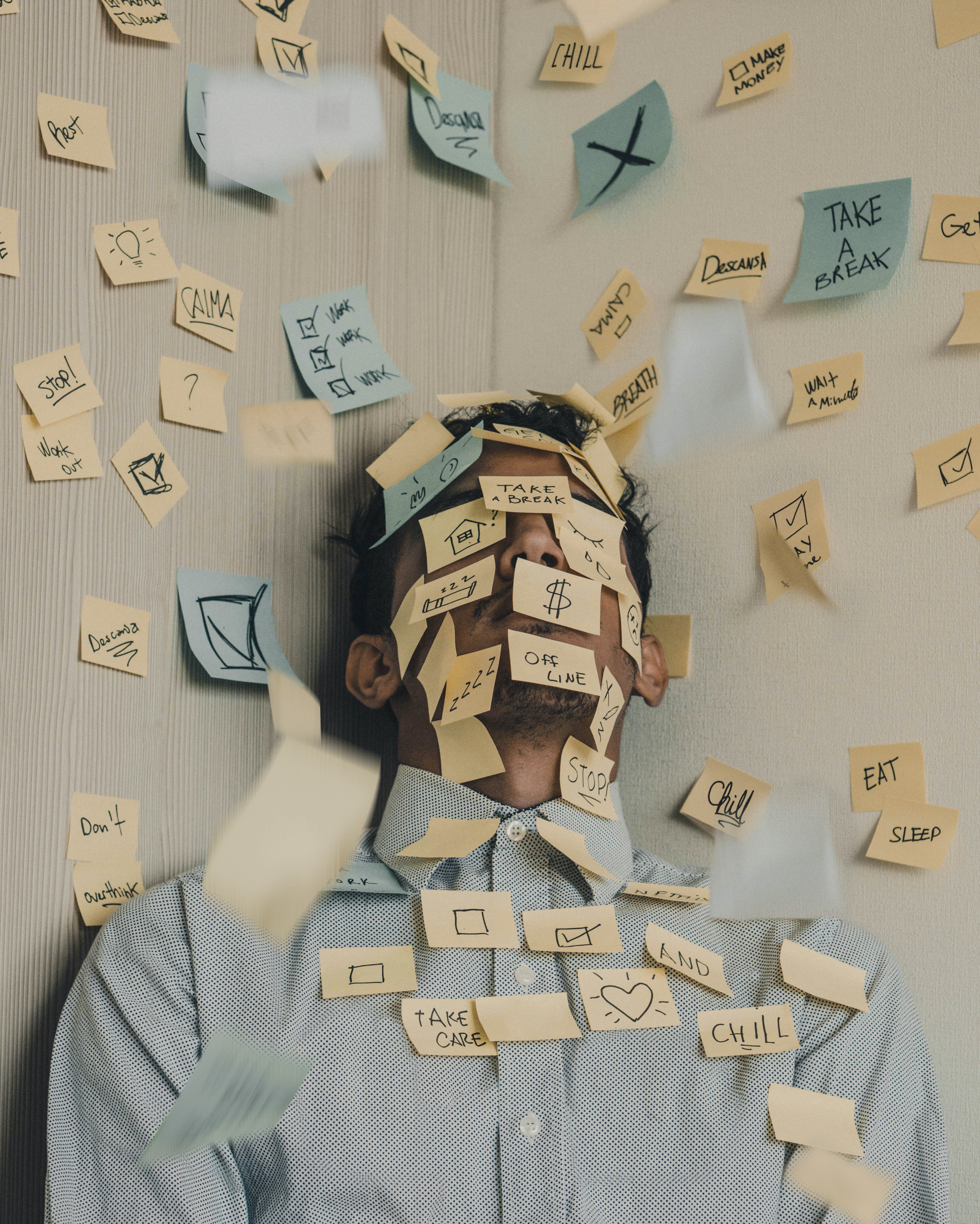 Young man covered in sticky notes, work overload