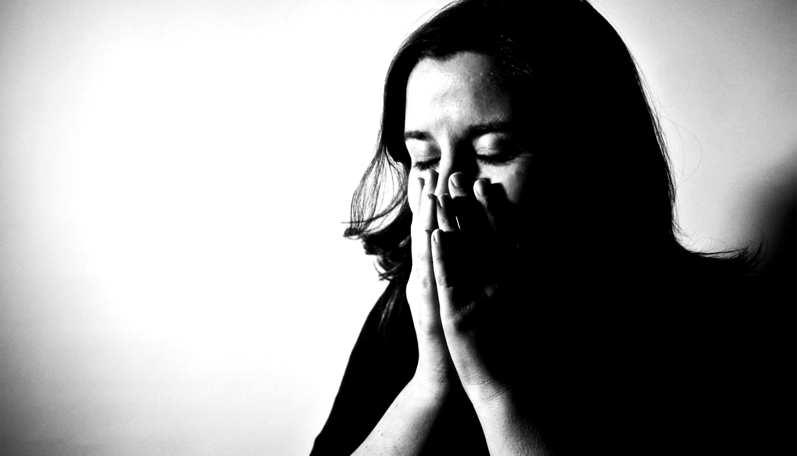 A black and white image of a hispanic woman with her face between her hands