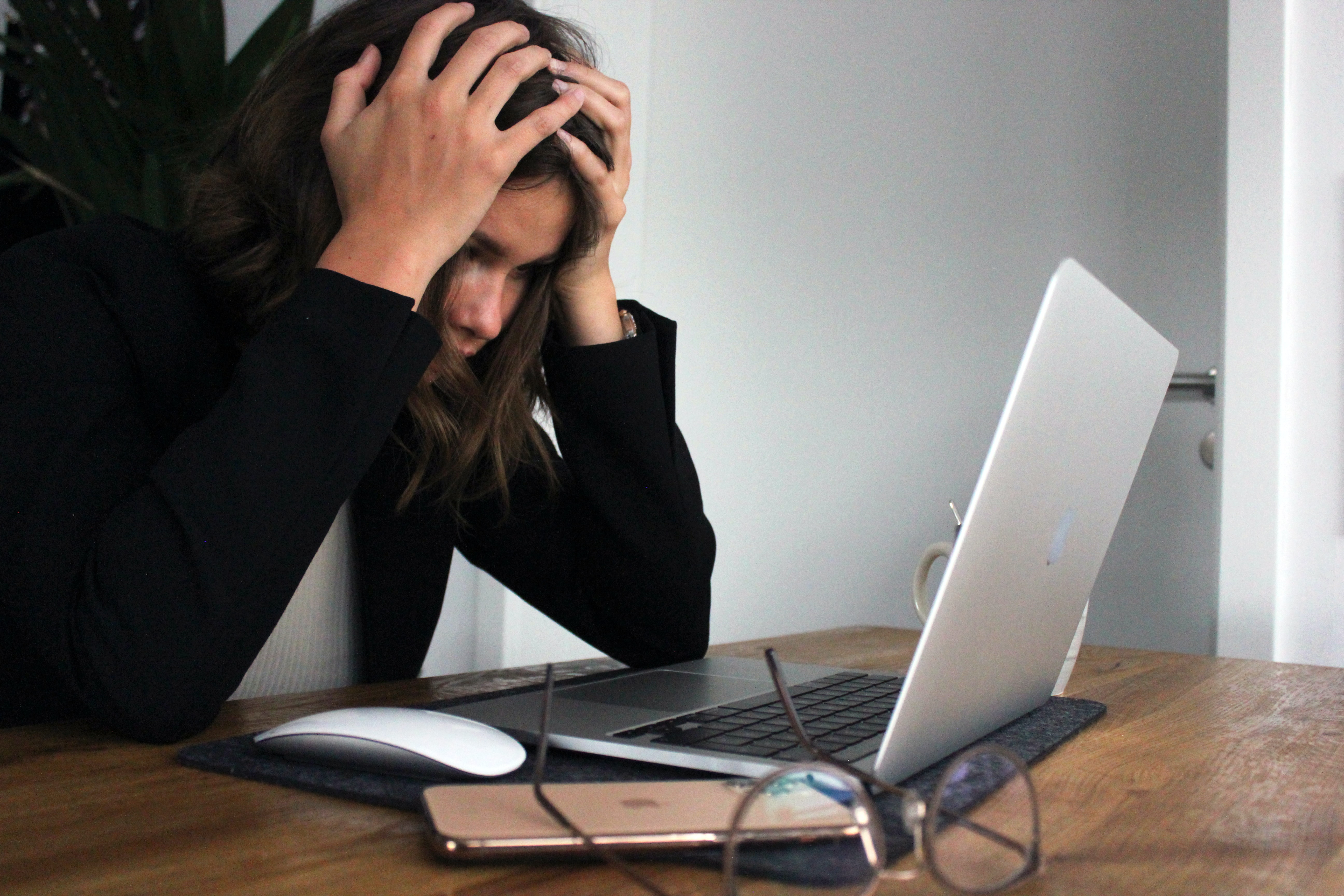 Workplace stress : A woman sitting in front of her computer with her head in her hands -
