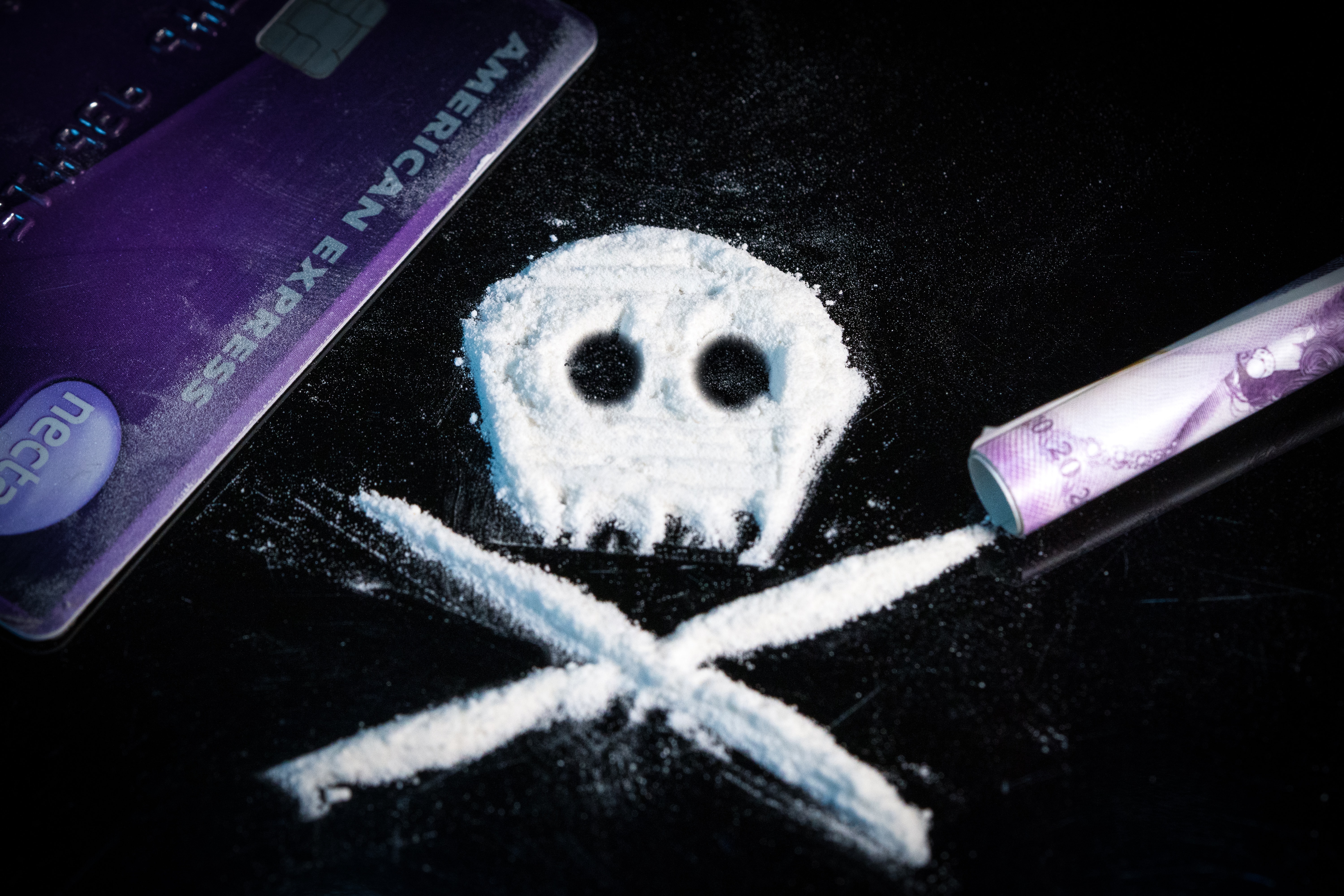 A skull and crossbones made out of cocaine powder on top of a mirror